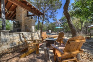 Un espacio al aire libre con patio, paredes de piedra, mobiliario de madera y chimenea de piedra.