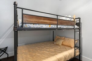 Una cama litera con cabecera de madera y una cama inferior con cubrecama acolchado.