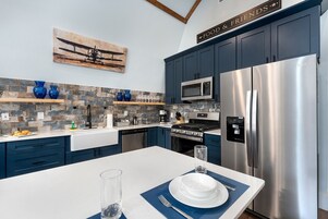 Cocina moderna con armarios azules, electrodomésticos de acero inoxidable y un salpicadero de piedra.