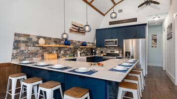 A modern kitchen with a central island, bar stools, a microwave, and a refrigerator.