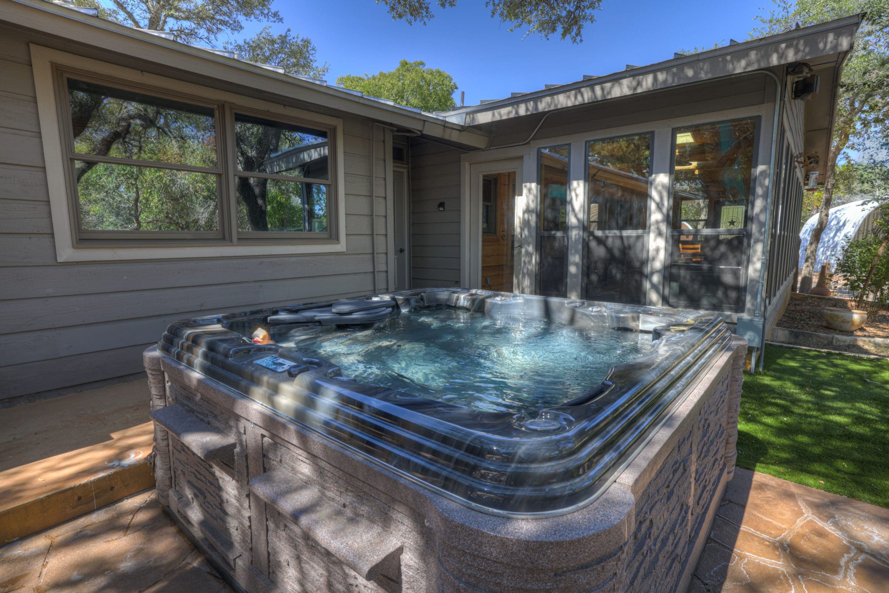 A hot tub in a backyard with a house in the background.