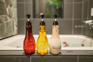 Tres botellas de jabón corporal, champú y acondicionador sobre un repisa de azulejos.