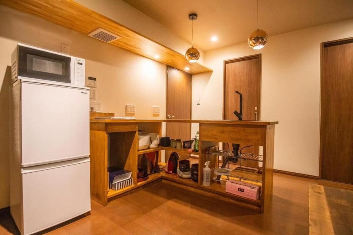 Una cocina compacta con un refrigerador blanco, armarios de madera y una estantería empotrada.