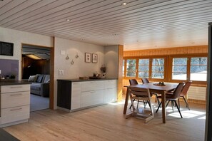 Eine moderne Küche mit Essbereich, Holzboden und großen Fenstern.
