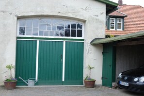 Een gebouw met een grote garageklep, een plant in een pot en een auto voor de deur.