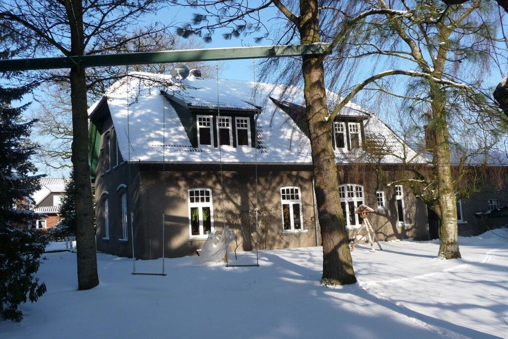 Ein schneebedecktes Haus mit einer großen Veranda und einer Schaukel.