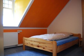 A single bed in a room with orange walls and a sloped ceiling. - Holiday apartment in Jade with barbecue (Jade)