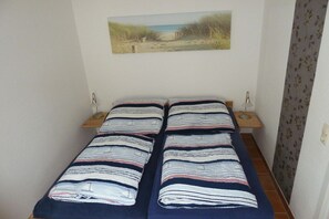 A small room with a bed, two bedside tables, and a wall-mounted picture. - 8 in the house cooling (Kühlungsborn)