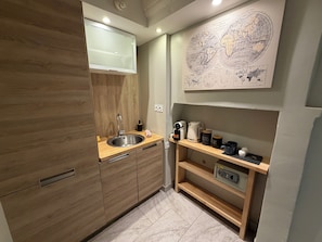 A modern kitchen with wooden cabinets, a stainless steel sink, and a coffee station. - Villa Ursuline: Charm and Comfort in the Heart of the City (Bayeux)
