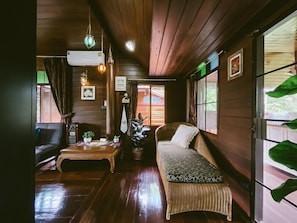 A cozy room with a sofa, a coffee table, and a potted plant. - Rommai Villa (Chiang Rai)