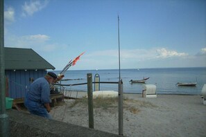 Ein Mann fischt an einem Steg, im Hintergrund ein Boot.