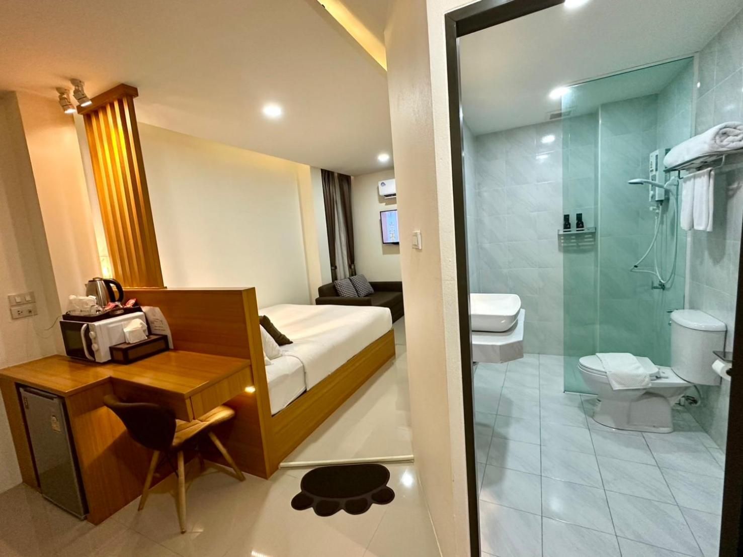 A hotel room with a bed, desk, chair, and a shower area.