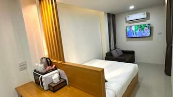 Ein Hotelzimmer mit einem Bett, einem Schreibtisch, einem Stuhl, einem Fernseher und einer Klimaanlage.