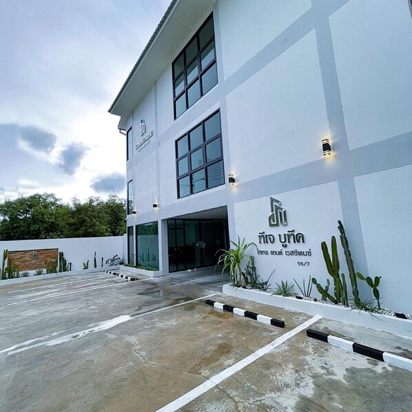 A modern building with a white facade, large windows, and a sign indicating a boutique hotel.