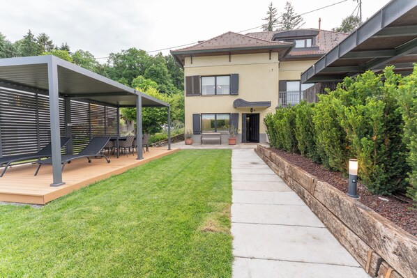 Une maison moderne à deux étages, dotée d’un patio couvert et d’une pelouse bien entretenue.