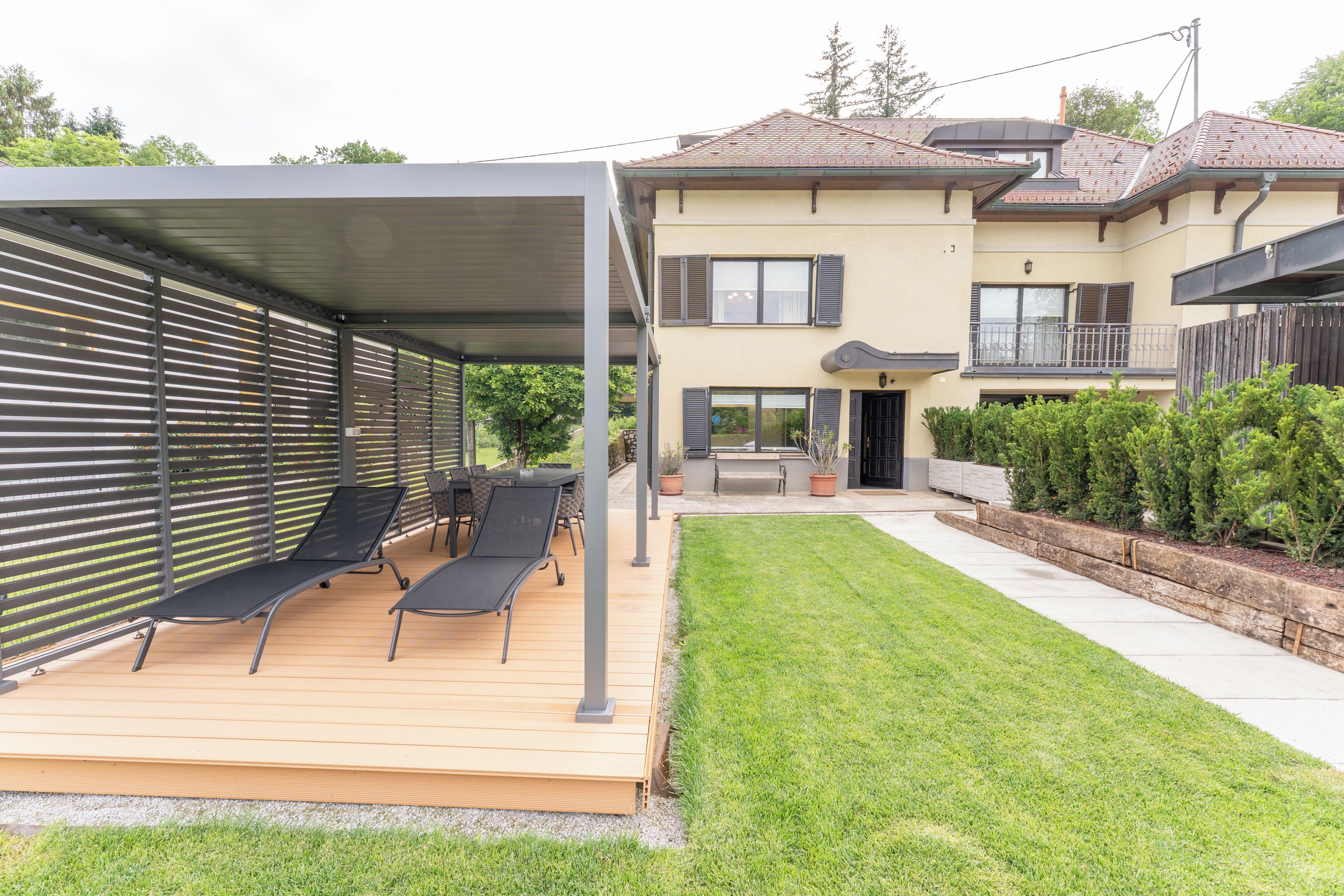 A covered patio with outdoor seating and a well-maintained lawn.