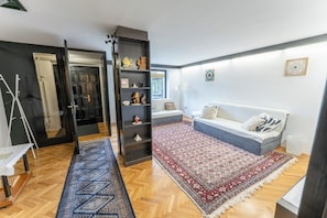 A living room with a sofa, a coffee table, a bookshelf, and a patterned rug.