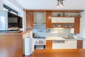 Una cocina moderna con armarios de madera, un microondas integrado, una estufa a gas y un lavavajillas.