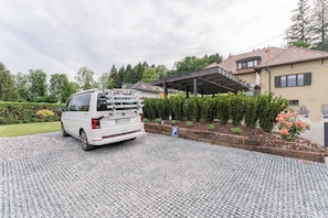 A white van parked in a gravel driveway with a blue parking sign.