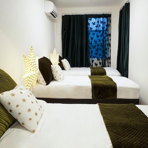 Quarto de hotel com duas camas, janela com cortinas de borboleta e aparelho de ar condicionado.