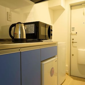 Uma cozinha compacta equipada com chaleira, micro-ondas e pequeno frigorífico.