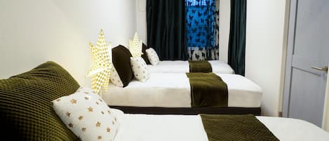 A hotel room with two beds, a window with curtains, and an air conditioning unit.