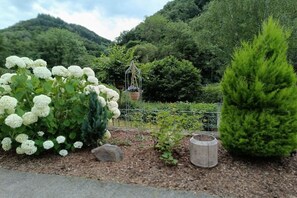 A garden with white hydrangea bushes, a coniferous tree, and a metal fence. - Holiday home with 4 bedrooms (Brodenbach  Ehrenburgertal)