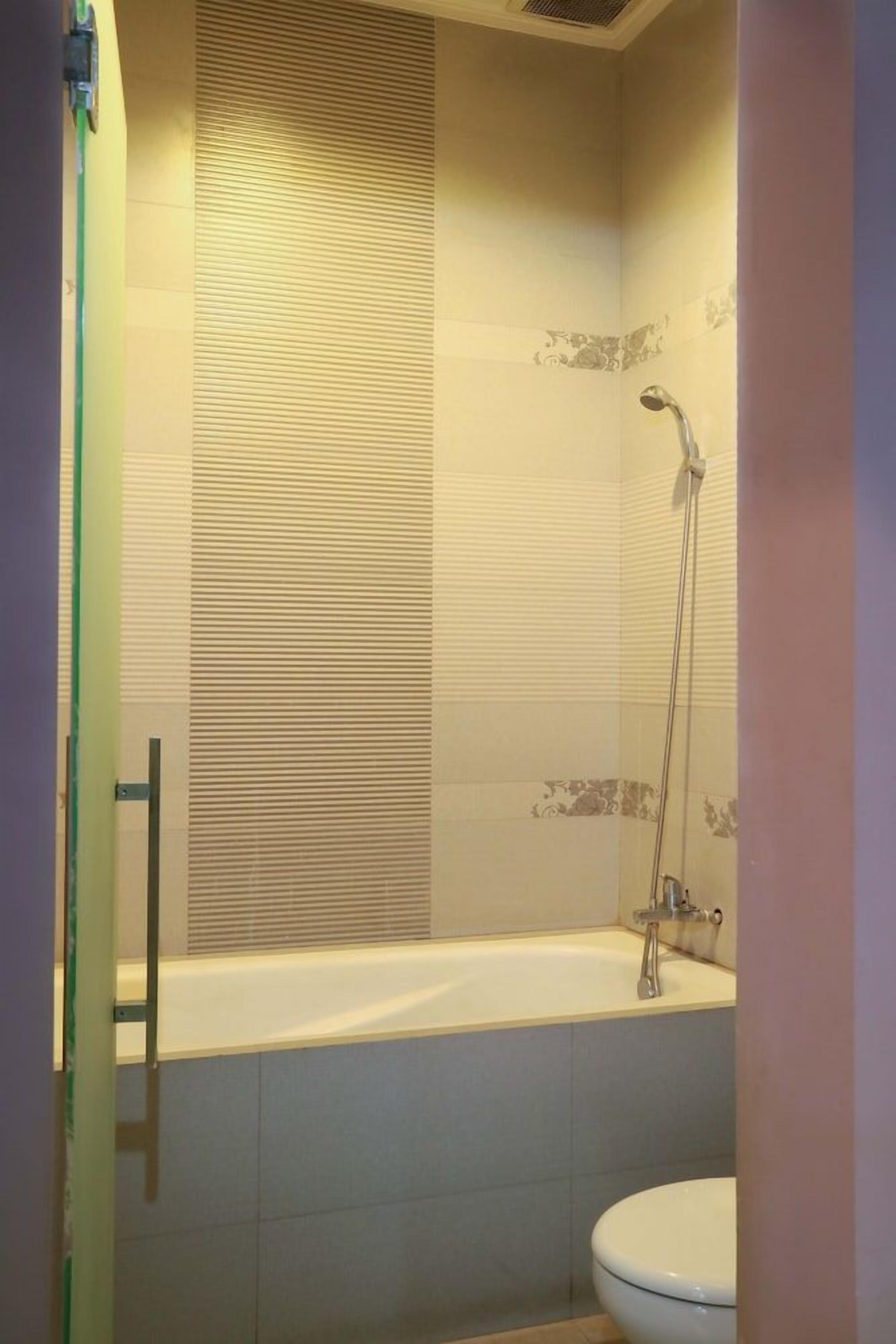 A bathroom with a bathtub, a toilet, and a shower area.