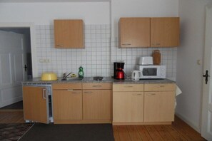 A compact kitchen with wooden cabinets, a microwave, a kettle, and a coffee maker. - Apartment "Baltic Sea Dune" (Kühlungsborn)