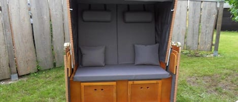 Un banco de madera con dosel, asientos acolchados y compartimentos de almacenamiento.