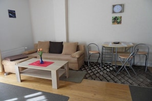 A furnished living room with a sofa, a coffee table, and a dining area with a table and chairs. - Apartment "Baltic Sea Dune" (Kühlungsborn)