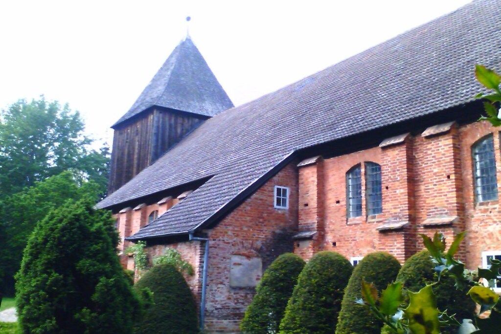 A historic building with a steeply pitched roof, brick walls, and a prominent tower.
