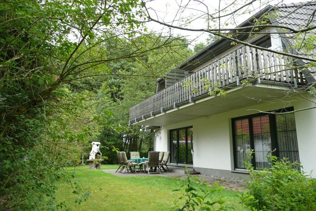 Une maison avec un balcon, une pelouse et un jardin.