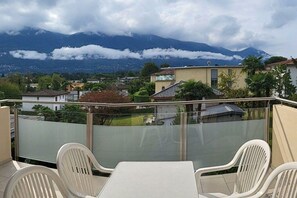 Ein Balkon mit Tisch und Stühlen, der auf ein Wohngebiet mit Häusern und einem Berg im Hintergrund blickt.