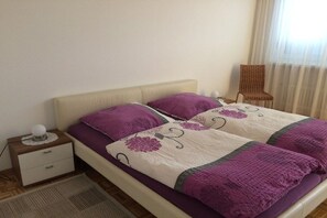 Ein Bett mit Kopfteil, zwei Kissen, ein Nachttisch mit Lampe und ein Sessel.