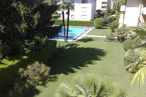 A residential area with a swimming pool surrounded by well-maintained lawns and trees. - Holiday apartment with 1 bedroom (Ascona)