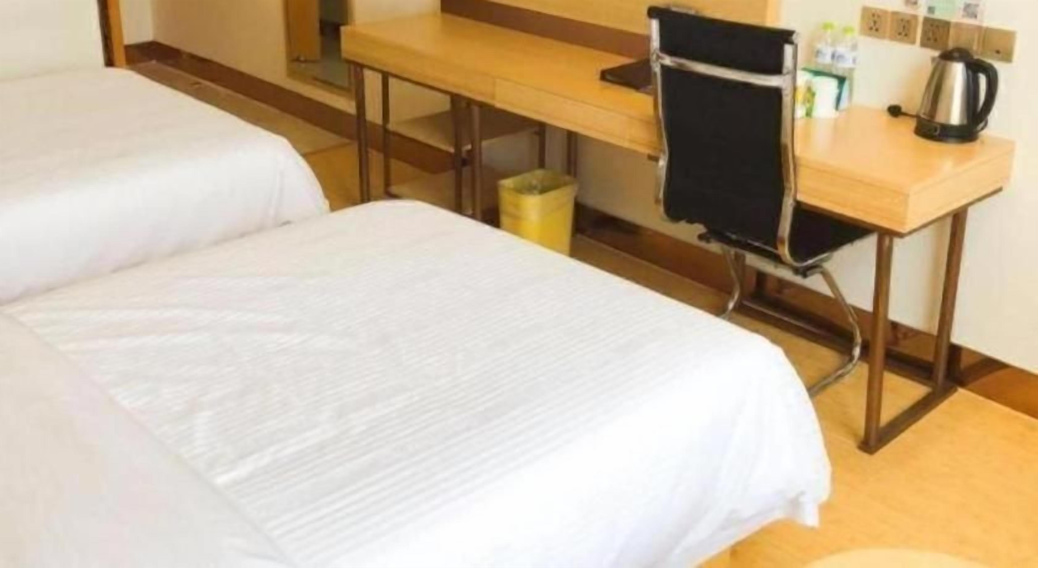 A hotel room with two beds, a desk, a chair, and a coffee maker.