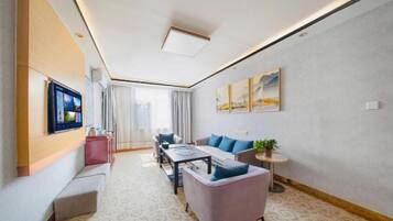 A modern living room with a sofa, a coffee table, and a TV mounted on the wall.