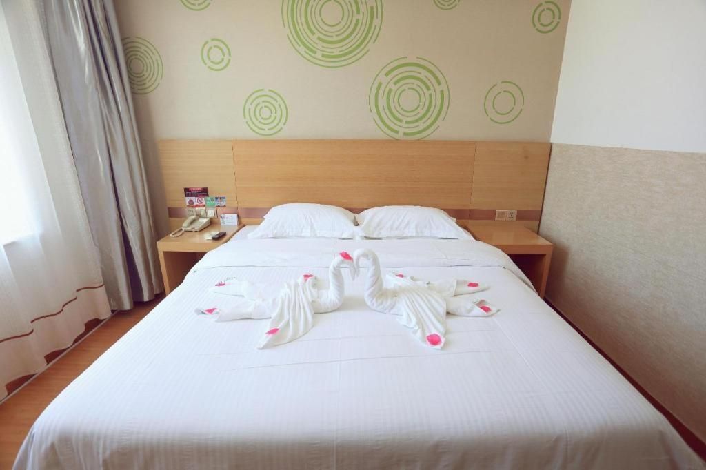 A hotel room with a bed, two nightstands, a telephone, and a wall with circular patterns.