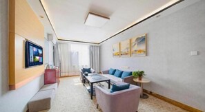 A modern hotel room with a flat-screen TV, a sofa, a dining table, and a small side table. - Greentree Inn Binzhou Wudi Ginza Square Express Hotel (Binzhou)