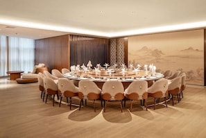 A round dining table with chairs, a large painting, and a view of the outdoors.