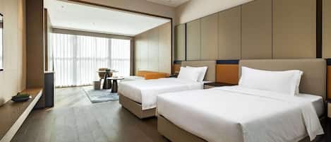 Habitación de hotel con dos camas, una mesita y vistas al exterior.