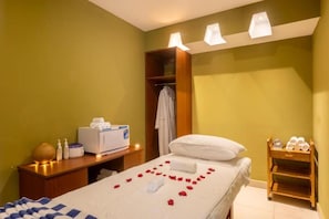 A hotel room with a bed, a wooden nightstand, a vanity with toiletries, and a robe hanging on a rack. - Hermosa Garden Hotel & SPA (Nairobi)