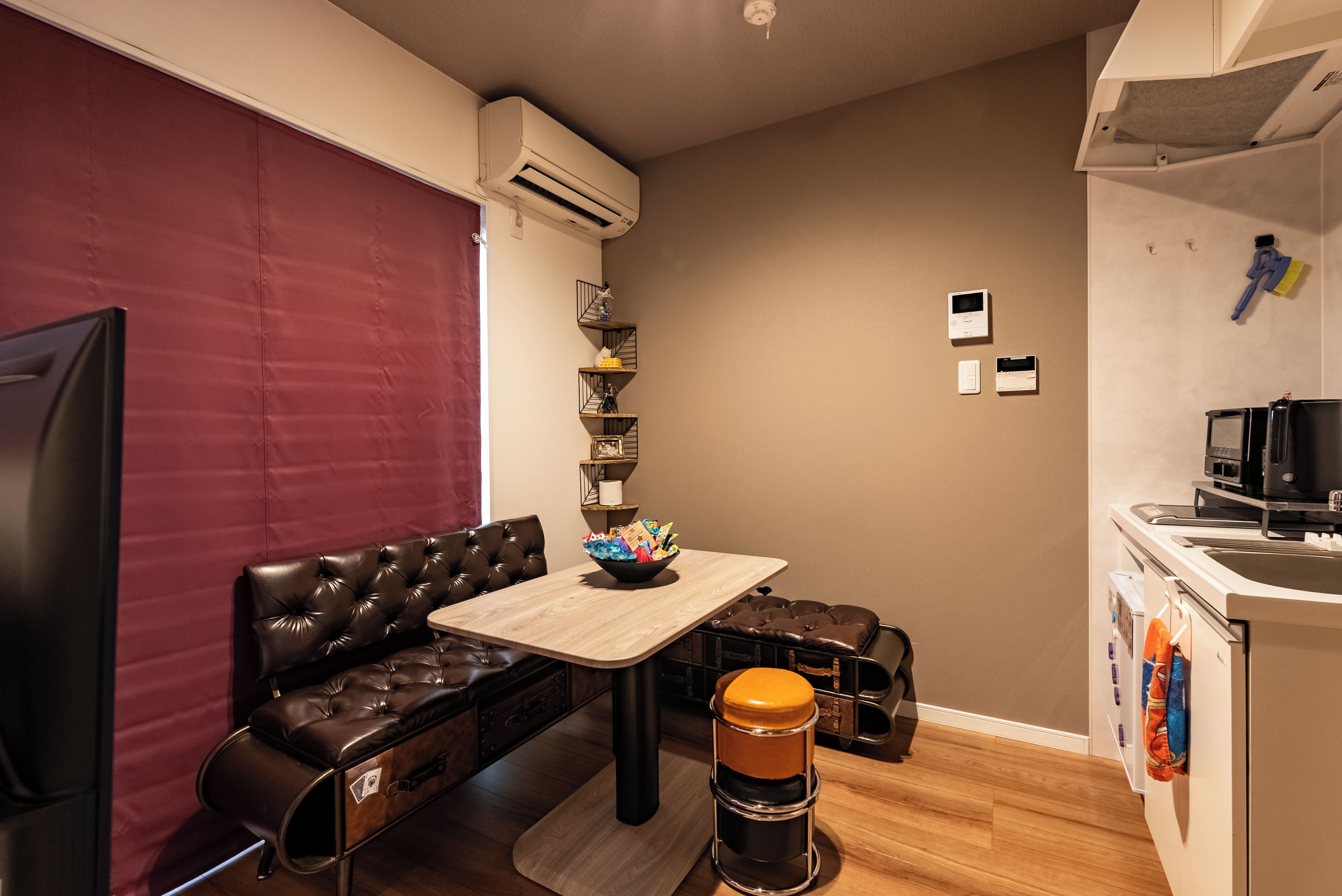 A compact living space with a sofa, a small table, a coffee machine, and a kitchenette.