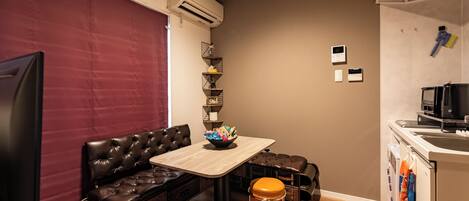 A compact living space with a sofa, a small table, a coffee machine, and a kitchenette.