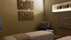 Habitación con dos camas, cabecero de madera, una obra de arte colgada en la pared y una mesita con una toalla.