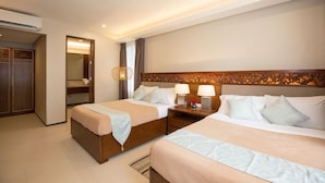 Una habitación de hotel con dos camas, un armario, un espejo y una mesita de noche con lámparas.