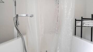 Une baignoire équipée d’un pommeau de douche, d’un porte-serviettes et d’un mur à surface texturée.