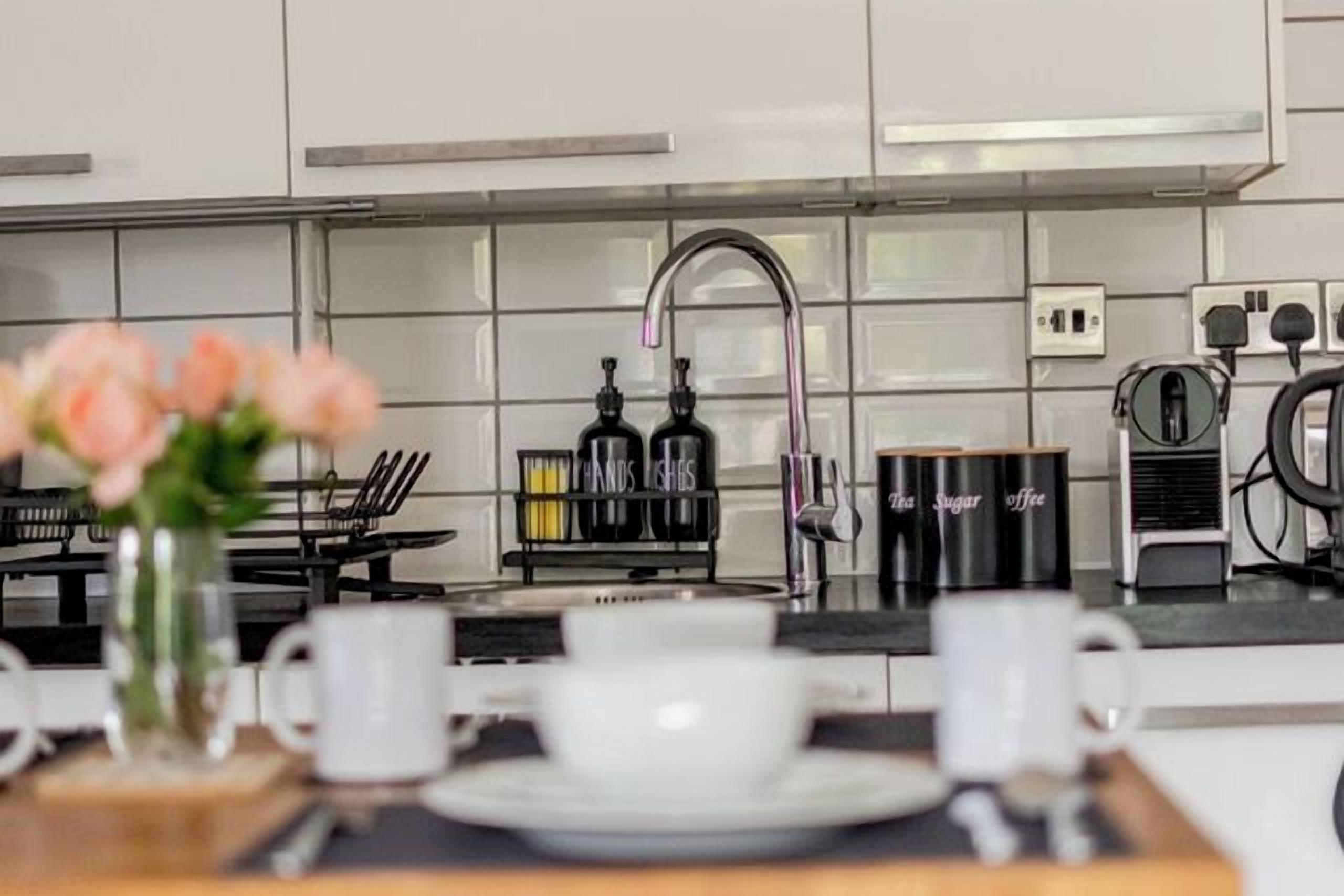 A modern kitchen with a coffee machine, a sink, and a vase with flowers on the counter.