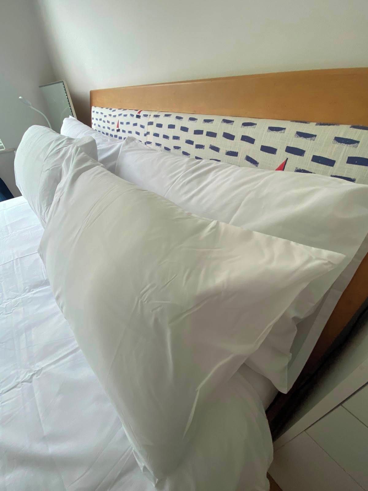 A bed with white bedding and a headboard with a geometric pattern.